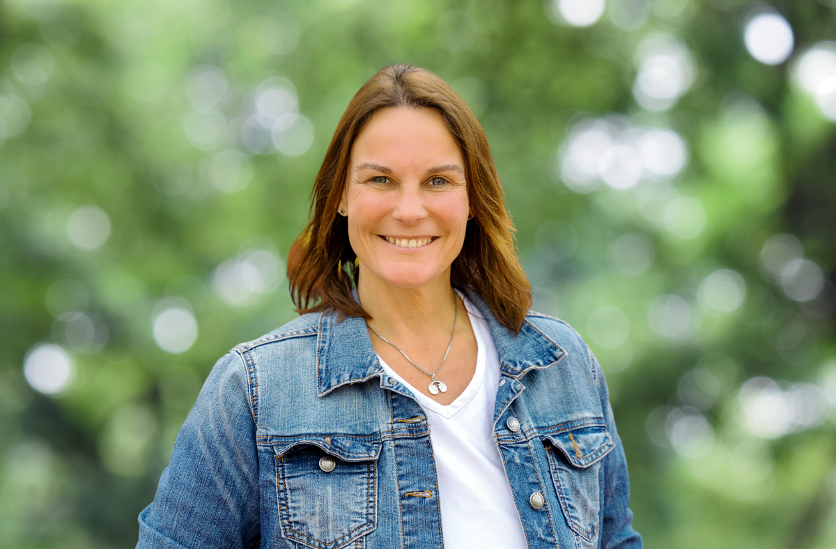 Foto von Katy Walther in blauer Jeansjacke vor grünem Hintergrund